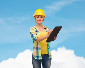 Image showing smiling woman in helmet with clipboard