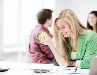 Image showing smiling student girl eating apple at school