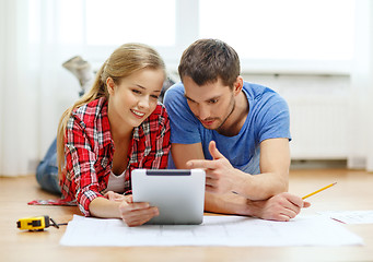 Image showing smiling couple looking at tablet pc at home