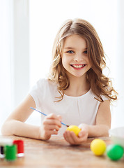 Image showing smiling little girl coloring eggs for easter