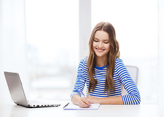 Image showing smiling teenage girl laptop computer and notebook