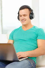 Image showing smiling man with laptop and headphones at home