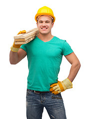 Image showing smiling manual worker in helmet with wooden boards