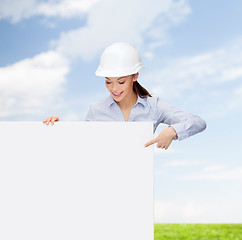 Image showing businesswoman in helmet pointing finger to board