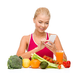 Image showing woman with vegetables pointing at smartphone