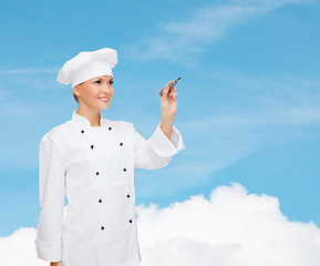 Image showing smiling female chef writing something on air