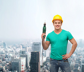 Image showing smiling manual worker in helmet with drill machine