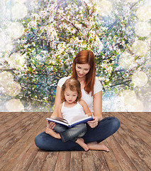 Image showing happy mother with adorable little girl and book