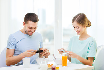 Image showing smiling couple with smartphones taking picture