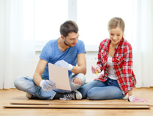 Image showing smiling couple measuring wood flooring