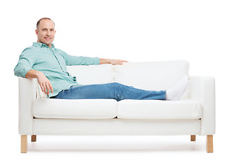 Image showing smiling man lying on sofa