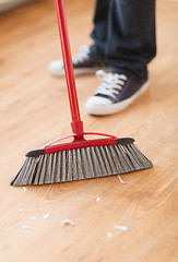 Image showing close up of male brooming wooden floor
