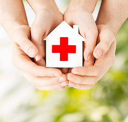 Image showing hands holding paper house with red cross