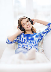 Image showing smiling young girl in headphones at home