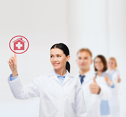 Image showing smiling female doctor pointing to hospital sign