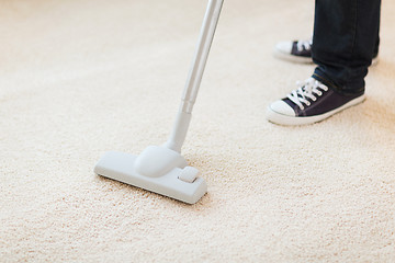 Image showing close up of male hoovering carpet