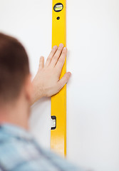 Image showing close up of male with spirit level mesuring wall