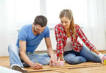 Image showing smiling couple measuring wood flooring