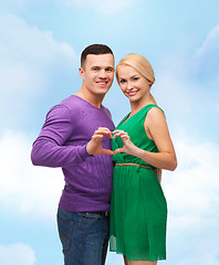 Image showing smiling couple showing heart with hands