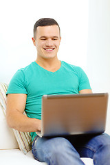 Image showing smiling man working with laptop at home