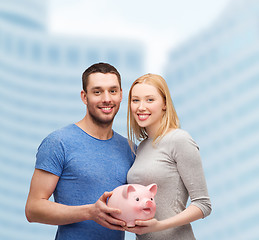 Image showing smiling couple holding big piggy bank