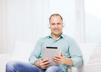 Image showing smiling man with tablet pc and headphones at home