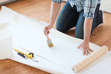 Image showing closeup of male hands smearing wallpaper with glue