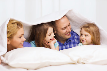 Image showing happy family with two kids under blanket at home