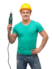 Image showing smiling manual worker in helmet with drill machine