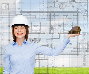 Image showing businesswoman in helmet holding house on palm