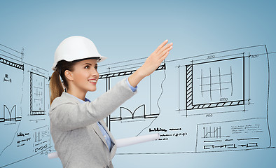 Image showing smiling architect in white helmet with blueprints