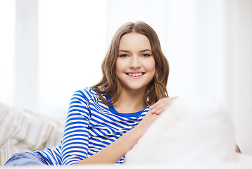Image showing smiling teenage girl sitting on sofa at home