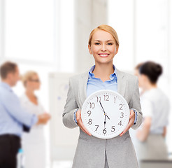 Image showing smiling businesswoman with wall clock