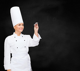 Image showing smiling female chef writing something on air