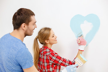 Image showing smiling couple painting small heart on wall