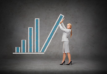 Image showing young smiling businesswoman pushing up chart bar