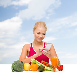 Image showing woman with vegetables pointing at smartphone