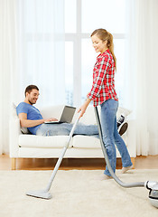 Image showing smiling woman with hoover and man with laptop