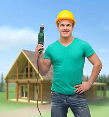 Image showing smiling manual worker in helmet with drill machine