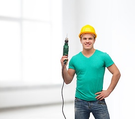 Image showing smiling manual worker in helmet with drill machine