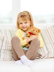 Image showing smiling girl with teddy bear sitting on sofa