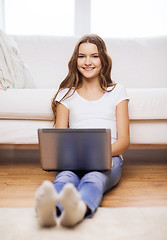 Image showing smiling teenage girl with laptop computer at home