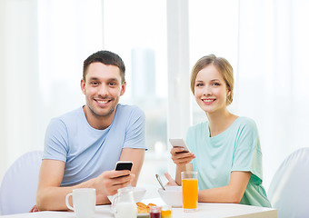 Image showing smiling couple with smartphones reading news