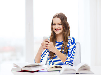 Image showing smiling student girl with smartphone and books