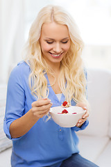 Image showing smiling woman with bowl of muesli having breakfast