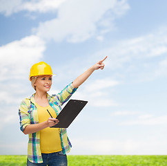 Image showing smiling woman in helmet with clipboard