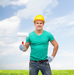 Image showing smiling manual worker in helmet with paint roller