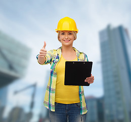 Image showing smiling woman in helmet with clipboard