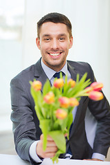 Image showing smiling handsome man giving bouquet of flowers