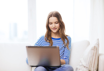 Image showing smiling teenage girl with laptop computer at home